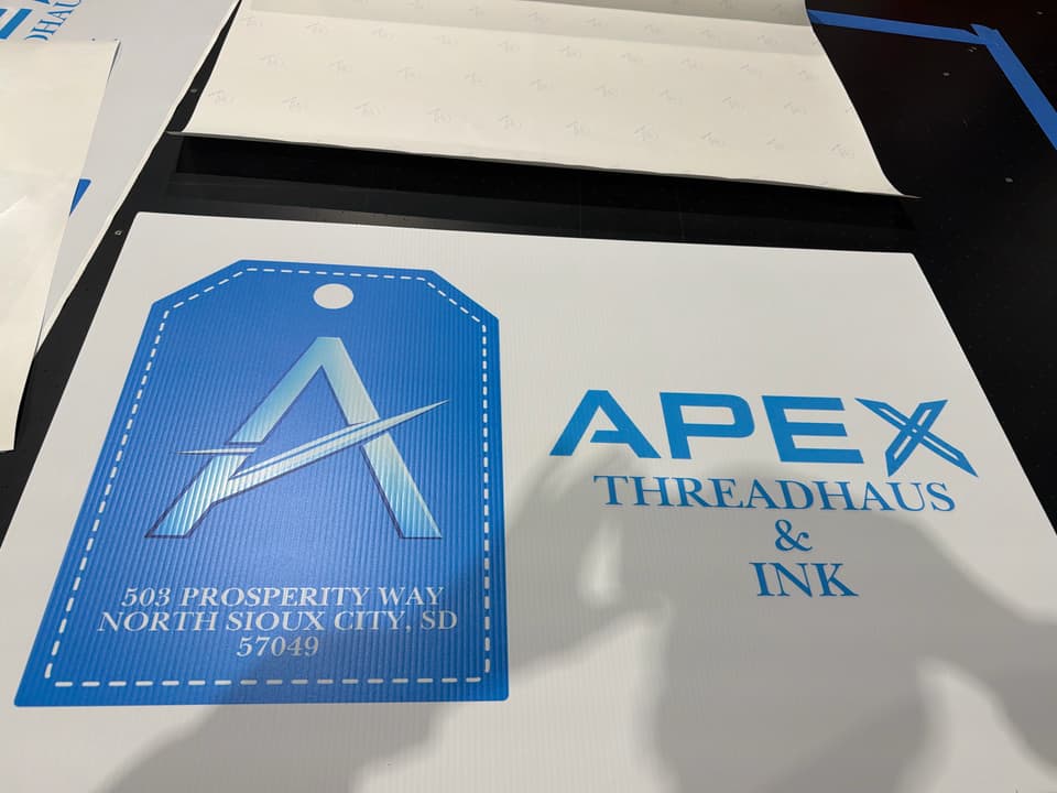 Apex Threadhaus & Ink sign printed on white board, on the print table